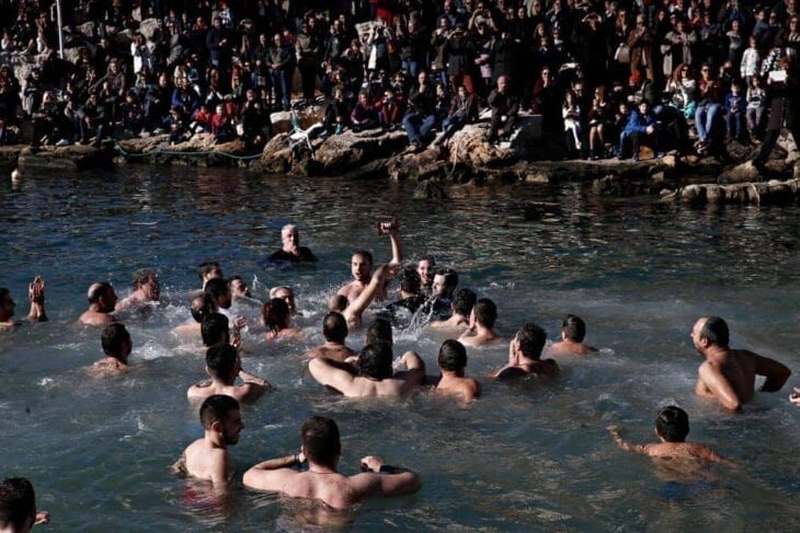 Schwimmer springen, um das Kreuz im gefrorenen Wasser zu fangen