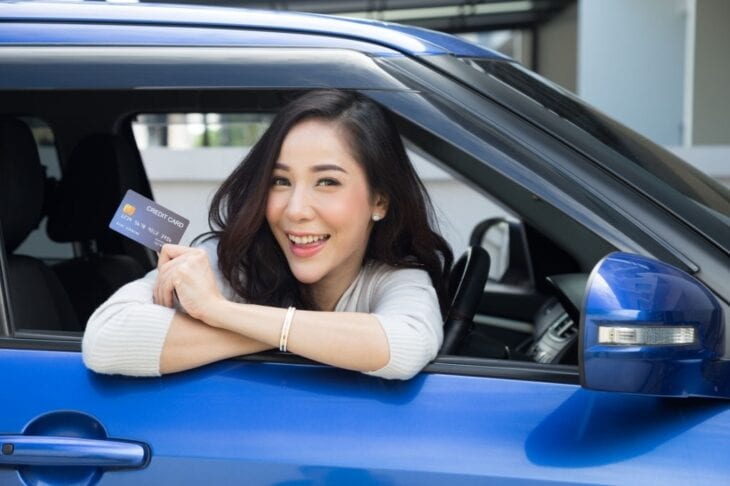 Vrouw met een kredietkaart in de auto